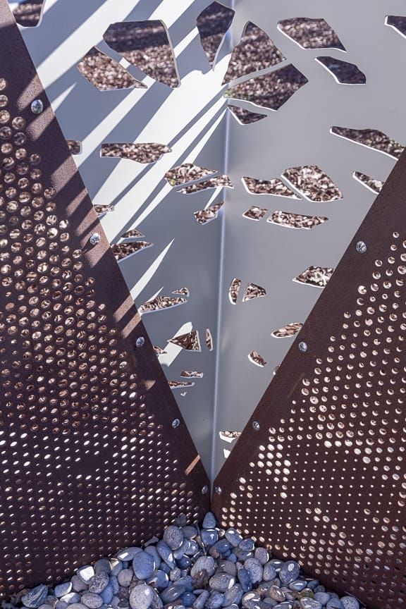 The fence is comprised of dual-sided clear anodized aluminum and dual-sided Zahner Solanum™ weathering steel panels.