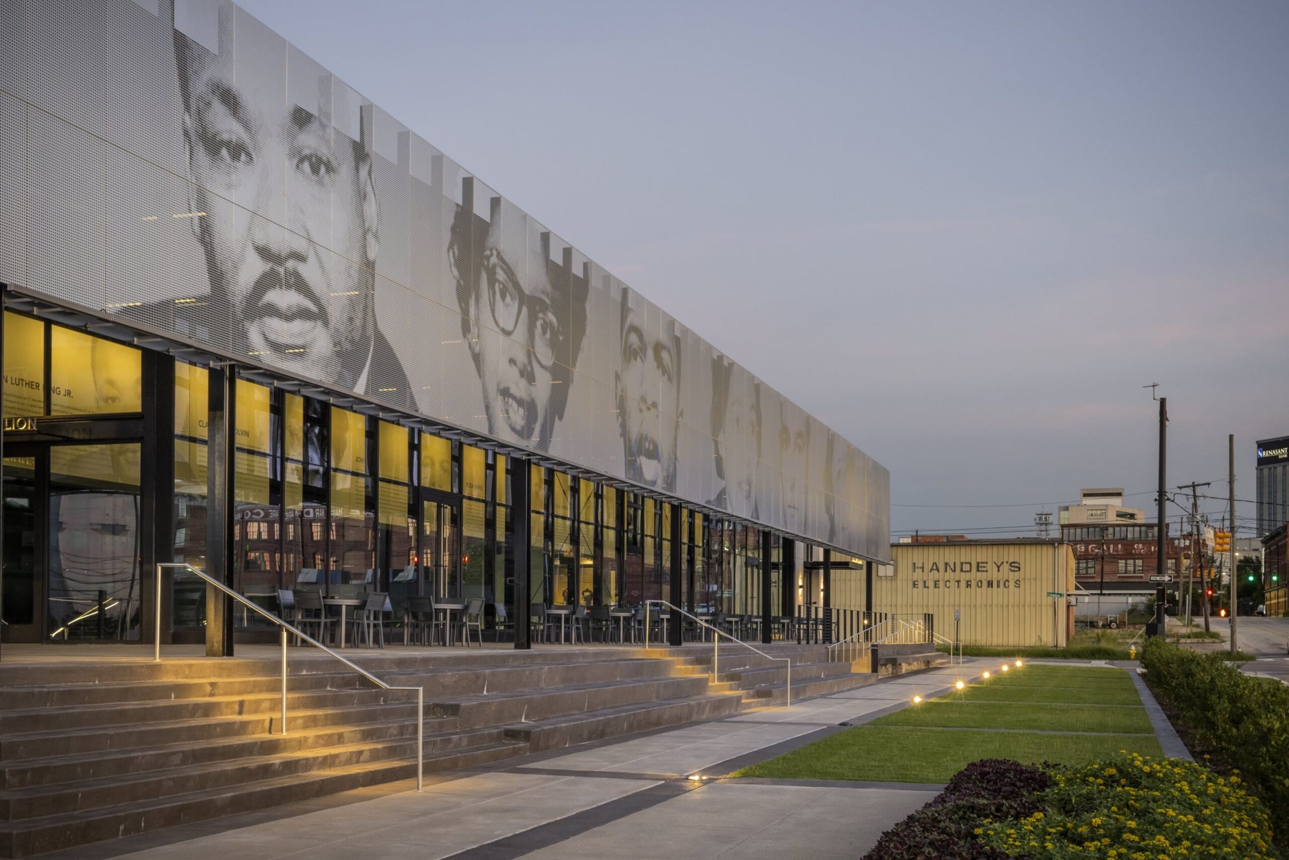 The iconic figures depicted on the EJI Legacy Pavilion ImageWall include Martin Luther King Jr., Claudette Colvin, John Lewis, Rosa Parks, Jonathan Daniels, Jo Ann Robinson, and E.D.
